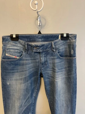 Diesel jeans - Snygga blå bootcut jeans från diesel med tvättade detaljer. Klassisk femficksmodell, låg midja och markerade bakfickor. Jeansen är tillverkade i mjukt denim och har en cool, avslappnad vibe. De är omsydda till bootcut. Midjemåttet är 39cm, skulle säga S/M