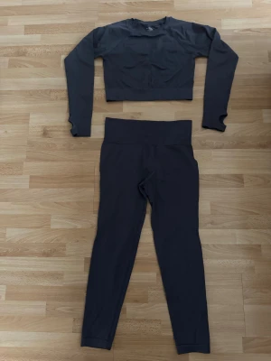 Purpur croppad set träningströja med leggins M - Supersnygg croppad träningströja med leggings i stretchigt syntetmaterial. Långärmad med tumhål i ärmsluten för extra komfort. Perfekt för gymmet eller löprundan, sitter tight och har en clean look.