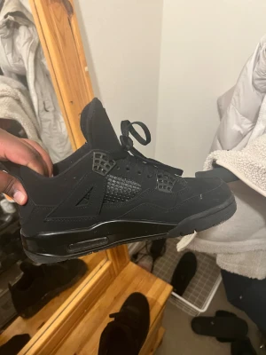 Svarta Nike Jordan 4 sneakers blackcat  - Priset kan diskuteras vid snabbt köp .Säljer ett par svarta Nike Jordan 4 sneakers med cool meshpanel på sidorna och klassisk Jumpman-logga på plösen. Skorna har snörning, platt sula och detaljer i syntet och mocka. Perfekt för dig som gillar streetwear och vill ha en clean look. 