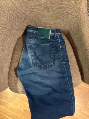 Jacob Cohën blå jeans med broderi - Snygga blå jeans från Jacob Cohën med coolt broderat citat på insidan och klassisk J-logga på grön patch baktill. Jeansen har kontrastsömmar, fem fickor och är tillverkade i mjukt stretchigt denim för skön passform. Jeansen är ca 105 cm långa
