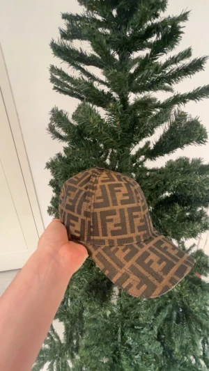 Fendi keps  - Snygg keps från Fendi med det klassiska FF-logomönstret i brunt och beige. Kepsen har böjd skärm och justerbar baksida. Materialet är slitstark😁❤️