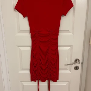 Röd kortklänning från H&M - Snygg röd kortklänning från H&M Divided i storlek XS. Passar S oxå. Klänningen har ribbad struktur, korta ärmar och cool snörning längs sidorna som ger en rynkad effekt. Stretchigt material som sitter tight och framhäver figuren. Perfekt för dig som gillar trendiga detaljer.
