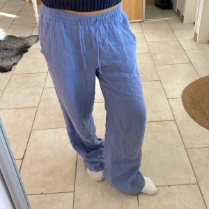 Blå linnebyxor med resår och snörning - Säljer ett par ljusblå linnebyxor med resår i midjan och snörning. Byxorna har en avslappnad, loose passform och vida ben. Fickor på sidorna för extra funktionalitet. Strl 36-38.  Knappt använd. 