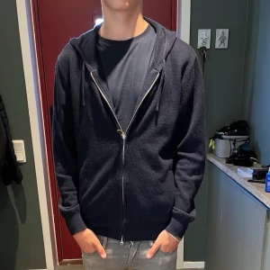 Mörkblå cashmere hoodie från Sayless - Snygg mörkblå hoodie från Sayless med huva och hel dragkedja framtill. Tröjan har långa ärmar och ribbade muddar vid ärmslut och nederkant. Perfekt för lugna dagar och mot kallt väder.