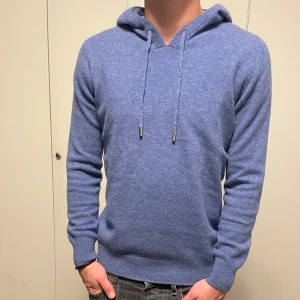 Blå Merinoull hoodie - Säljer nu denna stilrena och bekväma blåa hoodien i 100% merinoull! Storlek S. Modellen är 177 cm lång. Hoodien är sprillans ny och har inga defekter. 