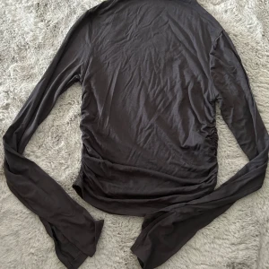  topp Gina Tricot S - Grå långärmad topp från Gina Tricot i mjuk bomullsmix. Snygg rynkdetalj på sidan som ger en cool twist. Perfekt till jeans eller kjol och funkar året runt. Enkel och stilren design med figurnära passform.