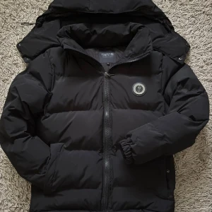 Trapstar jacka - Säljer en svart Trapstar pufferjacka. Den har avtagbar huva, dragkedja fram, broderad logga på ryggen och en patch på bröstet. Varm, stilren och perfekt för kalla dagar.