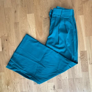 Emeraldgröna vida kostymbyxor - Säljer ett par kostymbyxor med hög midja och vida ben. Perfekta för dig som vill sticka ut med färg och stil hehe! Se bild två för mer exakt färg.