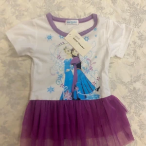 Frozen klänning med tyllkjol - Supersöt Frozen-klänning från Bear Leader med motiv av Elsa och Anna på bröstet. Överdelen är vit med lila kant vid halsen och korta ärmar, kjolen är i lila tyll som ger en prinsesskänsla. Perfekt för alla små fans av Frost!