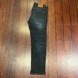 Jack & Jones Slim Straight Tim Jeans - Mörkblå jeans från Jack & Jones, modell Slim Straight Tim, 30W 30L. Klassisk femficksdesign med snygga slitningar framtill och kontrastsömmar. Jeansen har rak passform med en smal siluett och är tillverkade i mjukt denimtyg.