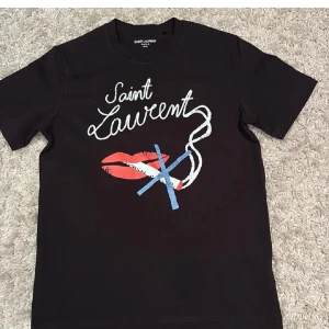 Svart Saint Laurent t-shirt med tryck - Tja.säljer denna väldigt snygga saint Laurent T-shirten , den är inprincip helt ny, byten funkar utmärkt 