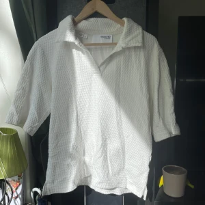 Piké från Selected Femme - Säljer en vit henley-skjorta från Selected Femme i storlek L. Skjortan har en krage, korta ärmar och är tillverkad i ett strukturerat bomullstyg som ger en cool och avslappnad vibe. Perfekt för dig som gillar stilrena och bekväma plagg.