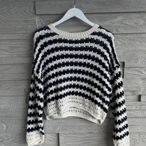 Randig stickad tröja från Pull&Bear - Säljer en stickad tröja från Pull&Bear i storlek M. Tröjan är randig i marinblått och vitt, har lång ärm och en avslappnad passform. Ribbad kant vid halsen och nederdelen ger extra detalj.