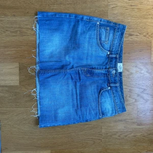 Blå jeanskjol med rå kant - Säljer en blå jeanskjol från med klassiska fickor fram och bak, bälteshällor och rå, fransig kant nertill. Kjolen har en snygg, enkel design💓