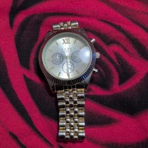 CODEX silverfärgad klocka med länk - Stilren klocka från CODEX med silverfärgad urtavla och klassisk länk i metall. Urtavlan har romerska siffror, tre mindre visartavlor och markerade index. Boetten är rund och armbandet har en glänsande finish som ger en lyxig känsla.