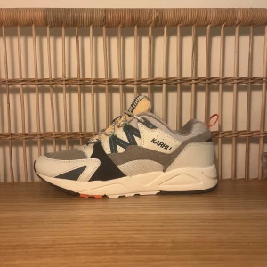 Karhu Fusion 2.0 sneakers grå/vit - Säljer ett par Karhu Fusion 2.0 sneakers i grått, vitt och beige med detaljer i mörkblått, grönt och orange. Skorna har mesh och mocka-paneler, snörning med mönstrade skosnören och en chunky sula. Perfekta för dig som gillar streetwear och snygga detaljer. Aldrig använda. Limited edition färg som inte säljs längre. Köpta för 1800