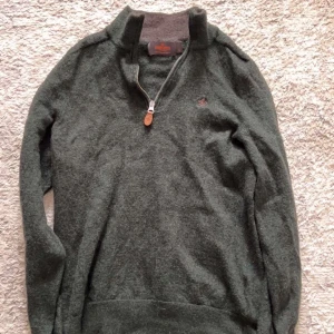 Mörkgrön tröja från Morris - Snygg mörkgrön tröja, passar även xss skulle jag säga. Tröjan har en half zip-dragkedja med läderdetalj och en broderad logga på bröstet. Perfekt för kyliga dagar och passar till det mesta. Långärmad och mjuk mot huden.