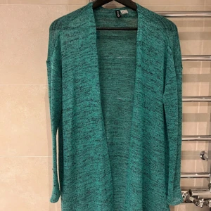 Turkos kofta från H&M Divided - Lång, öppen turkos kofta från H&M Divided. Koftan har en avslappnad passform, är långärmad och tillverkad i ett mjukt, stickat material. Perfekt att slänga över en t-shirt eller linne för en chill look.Rök och djurfritt hem.