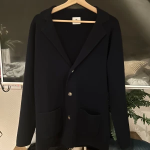 Mörkblå kofta från John Henric - En mörkblå kofta ifrån John Henric som är inprinsip i nytt skick endast använd ett få tal gånger, jag säljer den för att den inte sitter bra längre, den är väldigt bra skick 