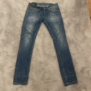 Blå slim fit jeans från Dondup - Säljer ett par blå slim fit jeans från Dondup med snygg tvätt och klassiska fem fickor. Jeansen har en smal passform och normal midja, tillverkade i mjukt denimtyg som sitter skönt. Perfekta för dig som gillar en modern och stilren look.