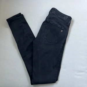 Replay Hyperflex svarta jeans - Svarta Replay Hyperflex jeans i modellen New Luz. Jeansen har en klassisk femficksdesign, silverfärgade detaljer och stretchigt material för extra komfort. Snygg passform med smal siluett och diskret Replay-logga på bakfickan.