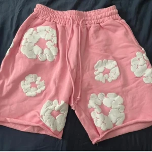 Rosa shorts från Denim Tears med blommor - Säljer äkta rosa shorts från Denim Tears med vita, fluffiga blommor över hela plagget. Priset går absolut o diskutera!!