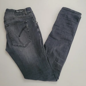Grå jeansbyxor från Dondup - Snygga grå jeansbyxor från Dondup i klassisk femficksmodell. Byxorna har en mörkgrå tvätt med lätt slitning och raka ben. Detaljer som Dondup-logga på linningen och kontrastsöm på bakfickan ger en unik look. .