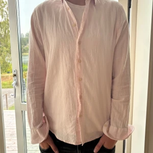 Ljusrosa linneskjorta från Macson - Säljer en ljusrosa skjorta från Macson i 100% linne. Skjortan har klassisk krage, knappar framtill och långa ärmar. Perfekt för dig som gillar en avslappnad men ändå stilren look. Passformen är normal och materialet känns svalt och luftigt.
