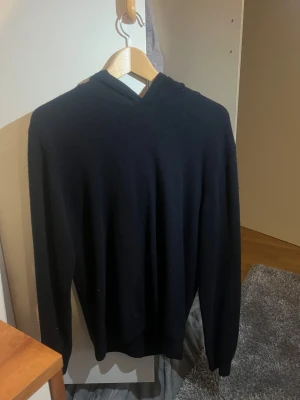 Marinblå cashmere hoodie  - Marinblå hoodie med lång ärm och huva, tillverkad i mjuk och varm 100% cashmere material. Enkel och stilren design utan synliga detaljer eller mönster, perfekt för dig som gillar minimalistiskt och comfy plagg. Passar dig som vill ha en klassisk look med extra mysfaktor. Nypris-1700kr/mitt pris-750kr!