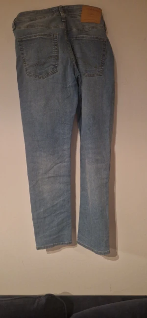 Ljusblå slim jeans från Jack & Jones - Säljer ett par ljusblå jeans från Jack & Jones, modell Slim Glenn. Jeansen har klassisk femficksdesign, raka ben och snygga kontrastsömmar. Tillverkade i bomull med en slim passform som sitter snyggt utan att bli för tighta. Slim/skiny 