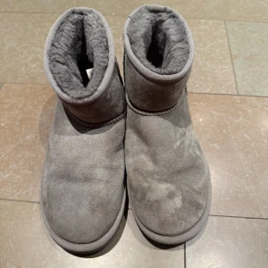 Grå UGG boots - Säljer ett par grå UGG boots i bra skick. De är supermysiga med mjukt foder inuti och perfekt för kalla dagar. Tillverkade i mocka med en robust sula som ger bra grepp. Perfekta för höst och vinter!