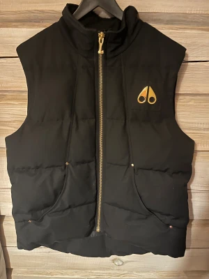 Moose Knuckles väst - Moose Knuckles väst i mycket bra skick i storlek XL med äkta pläterade guld detaljer nypris 6999kr med kvitto