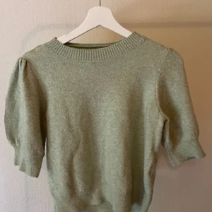 Ljusgrön stickad tröja med puffärm - Snygg ljusgrön stickad tröja med puffade ärmar och ribbad halsringning. Tröjan har en mjuk känsla och trekvartsärm,