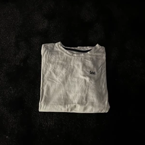 Vit t-shirt från Lee med broderad logga - Vit t-shirt från Lee med broderad logga på bröstet och en liten svart etikett med Lee-tryck vid nederkanten. Klassisk rund hals och korta ärmar. Tillverkad i mjuk bomull som känns skön mot huden. Perfekt för dig som gillar enkel och clean stil.