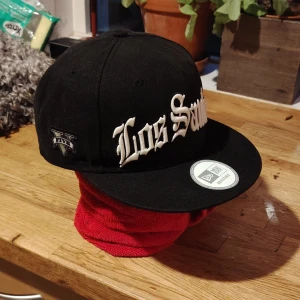 RockStar Games - GTA 5 - Los Santos keps collectors editionNew Era/Rockstar Games - Ultra rare samlar memorobilia officiellt licensierad av RockStar Games. Snygg svart keps från New Era med broderad text 'Los Santos' i vitt framtill och GTA V-logga på sidan. Kepsen har platt skärm och justerbar passform. Säljs för 75-100 euro på andra sidor. 