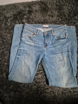Blå ripped jeans från Zara Woman - Snygga ljusblå jeans från Zara Woman Premium Denim Collection med slitna detaljer och flera ripped partier på benen. Modellen är smal och har klassisk femficksdesign, med normal passform och raka ben. Perfekt för dig som gillar en avslappnad streetstil.