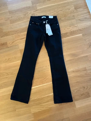  Nya Svarta bootcut jeans från Perfect Jeans - Svarta jeans från Perfect Jeans i bootcut-modell med låg midja. Klassisk femficksdesign, silverfärgade knappar och bakfickor med lock. Jeansen är tillverkade i stretchig bomullsblandning för en bekväm passform.jag köpte för 499kr