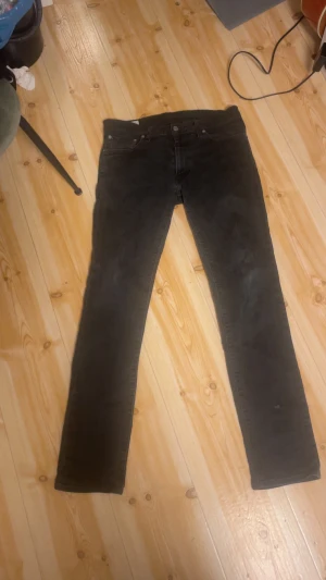 Svarta Levi's 511 jeans straight fit - Svarta jeans från Levi's modell 511 med klassisk femficksdesign och rakt snitt. Jeansen har en mörk ton, normal passform och är tillverkade i slitstarkt denim. Snygga detaljer som Levi's patch och röd etikett vid bakfickan.