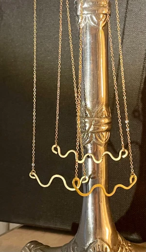 Guldiga halsband med vågig design - Två tunna halsband i guld med unika vågiga hängen. Kedjorna är smala och minimalistiska, medan hängena har en cool, lekfull form som sticker ut. Perfekt för dig som gillar trendiga och annorlunda smycken som ändå känns stilrena.