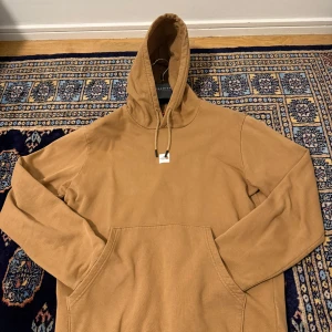 Beige hoodie från The North Face M - Säljer en beige hoodie från The North Face i storlek M. Tröjan har huva med snörning, stor magficka och ribbade muddar. Materialet är mjuk bomull och insidan är fleecefodrad för extra komfort. Logga på bröstet och ryggen ger en clean streetstil.