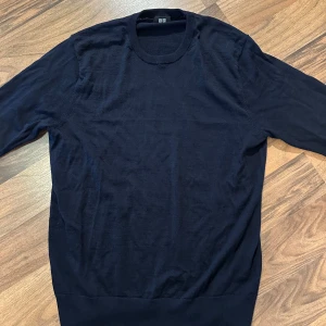 Mörkblå merinoulltröja från Uniqlo storlek M - Snygg mörkblå stickad tröja från Uniqlo i storlek M. Tröjan har rund hals och långa ärmar, perfekt för dig som gillar enkel och clean stil. Materialet är mjukt och lätt, vilket gör den skön att bära under höst och vinter. Knappt använd.