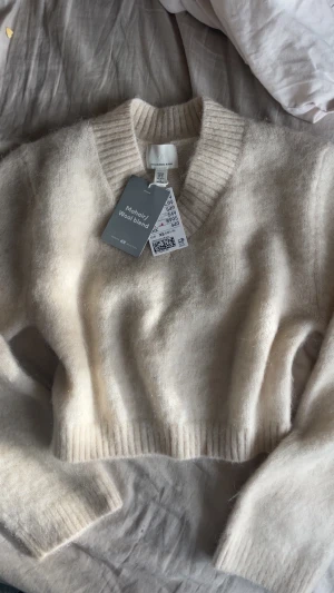 Ljusbeige croppad stickad tröja H&M - Supermjuk och fluffig ljusbeige stickad tröja från H&M i mohair/ullblandning. Croppad modell med bred ribbad v-ringad hals och långa ärmar. Perfekt nu för vintern! Original pris 549kr💕💕
