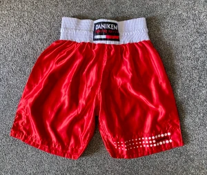 Röda boxningsshorts från Daniken - Snygga röda boxningsshorts från Daniken med bred vit resårmidja och coolt tryck med vita prickar på ena benet. Shortsen är tillverkade i 100% polyester och har en loose passform som ger grym rörelsefrihet. Perfekta för träning eller match!