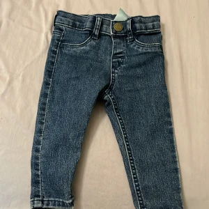 Blå jeansbyxor från H&M barn - Snygga blå jeansbyxor från H&M i klassisk femficksmodell med normal passform. Byxorna har mörk tvätt, kontrastsömmar och knappstängning fram. Perfekt för dig som gillar enkel och stilren denim-look.