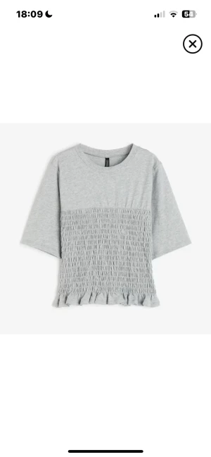 Hm smockad topp - Säljer en ljusgrå blus från Divided med smockad nederdel och volangkant. Nästan aldrig använd!