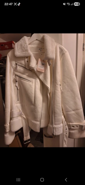 Vit aviator jacka från Missguided, stl 36 - Snygg vit jacka från Missguided i storlek 36. Jackan har bred krage, dragkedjor, bälte i midjan och detaljer vid ärmslut. Fodrad med mjukt teddyfoder och har en oversized look. Perfekt för kalla dagar när du vill vara både varm och trendig.