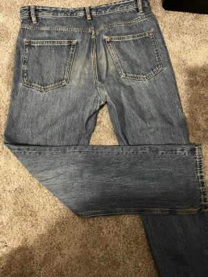  blå jeans loose fit W31 L32 kaphal - Säljer ett par jeans i blå tvätt med loose fit. Modellen har raka ben, fem fickor och bälteshällor. Jeansen är tillverkade i slitstarkt bomullsjeansmaterial och har en tidlös look som funkar till det mesta.