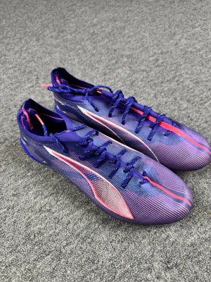Puma ultra 5 - Säljer ett par snygga fotbollsskor från Puma i lila med rosa och vita detaljer. Skorna har en smal och sportig siluett, snörning och låg profil. Ovandelen är i syntetmaterial för lätt känsla och bra bollkontroll. Perfekta för dig som vill sticka ut på planen!