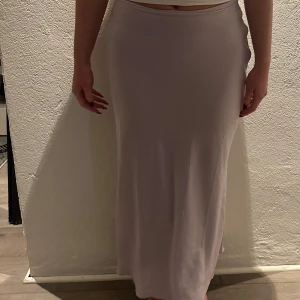 Lila satinkjol  - En stilren och enkel långkjol i ljuslila nyans. Kjolen har en rak passform som faller snyggt längs kroppen. Perfekt för dig som vill ha en kjol som är lätt att matcha. Aldrig använd.