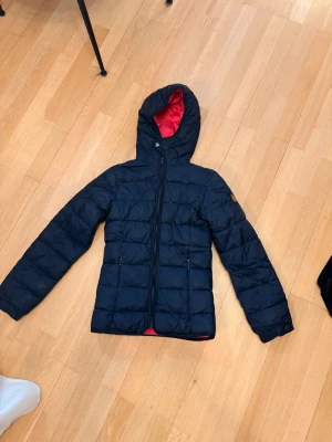 Svart dunjacka med rosa röd huva Replay - Pris kan fiskuteras Snygg svart dunjacka från Replay med röd insida på huvan. Jackan har dragkedja framtill, två fickor med dragkedja och Replay-logga på ärmen. Perfekt för kalla vinterdagar och har en modern, figurnära passform.